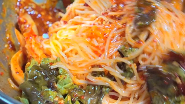 Spicy noodles being mixed in a bowl
