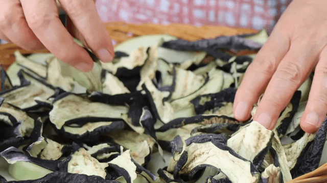 Placing dried eggplant on a bamboo basket