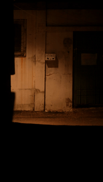 Dimly lit alley with a weathered wall