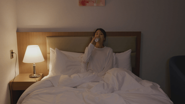 Woman relaxing in bed with a can coffee