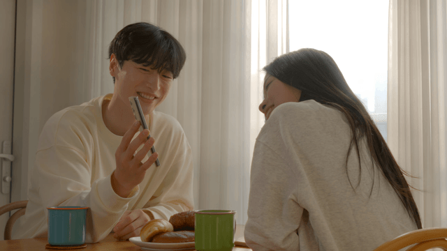 Couple looking at smartphone together at breakfast table