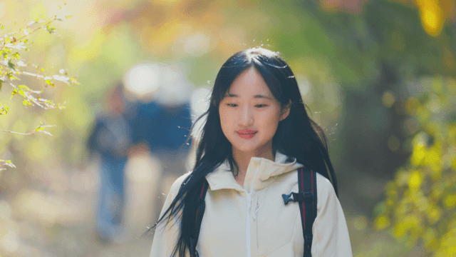 Woman walking on sunlit autumn hiking trail