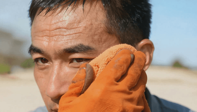Man wiping sweat with an orange towel