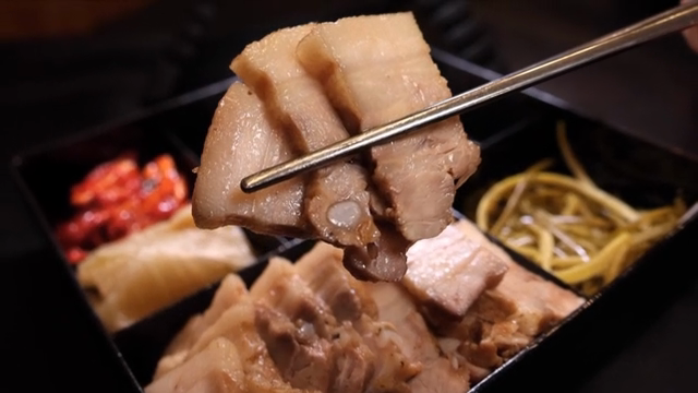 Chopsticks holding slices of bossam