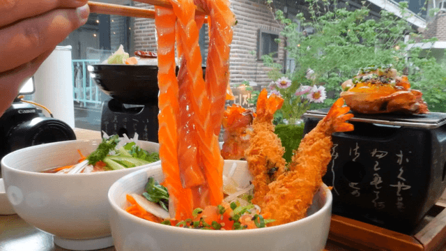 Long salmon sashimi lifted with chopsticks