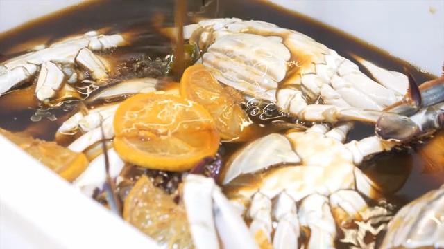 Making ganjang gejang by pouring soy sauce over raw crab