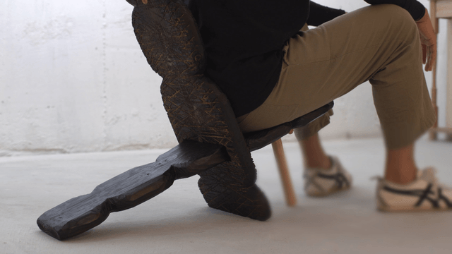 A person sitting on a unique wooden chair