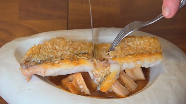 Fish being sliced on a white plate