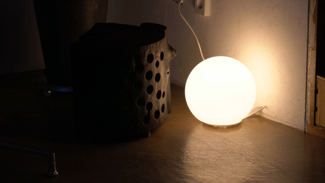 Glowing round lamp and unique wooden chair in a dim room