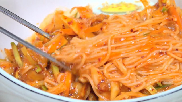 Spicy noodles being mixed in a bowl