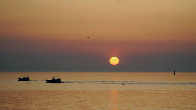 Fishing boats at sunrise on the calm sea