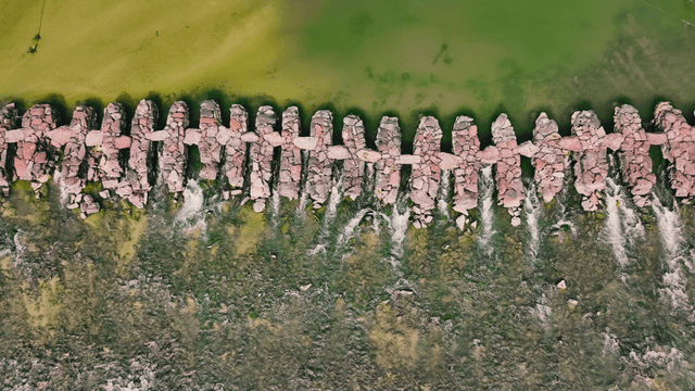 Aerial view of a stone bridge over a green river