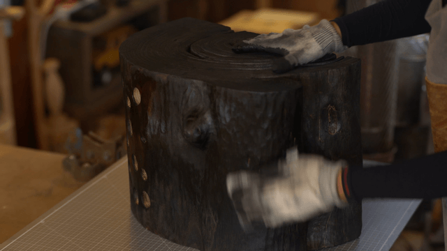Artisan polishing a black wooden sculpture with a cloth