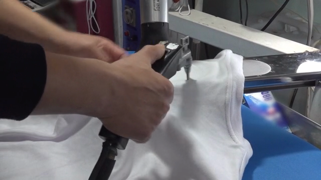 Hands ironing a white cloth indoors