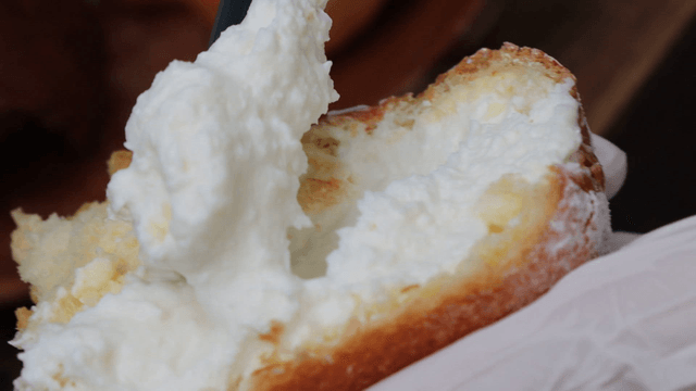Scooping cream from bread with a knife