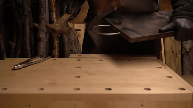 Artisan hammering metal wire into wooden board