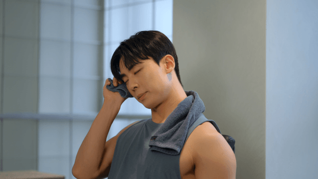 Young man resting during workout while wiping sweat