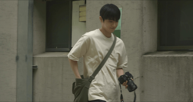 Man with camera passing by looking at poster on wall
