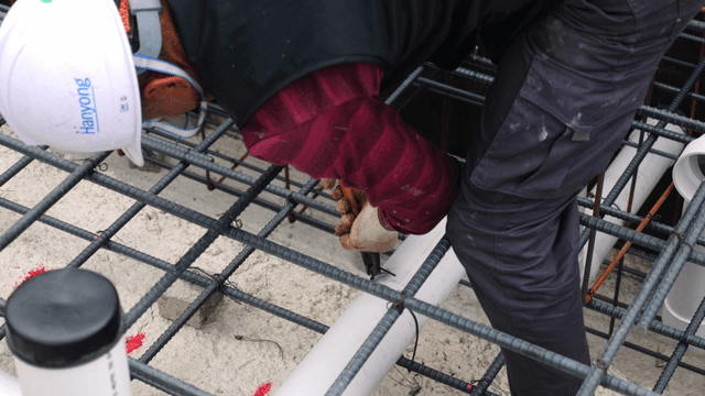 Worker securing pipes at a construction site