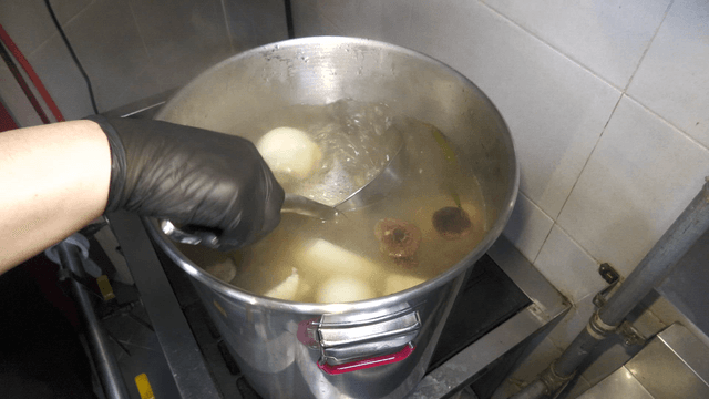 Ladle stirring broth with vegetables