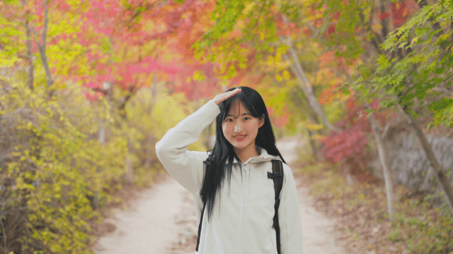 Young woman smiling while enjoying autumn foliage