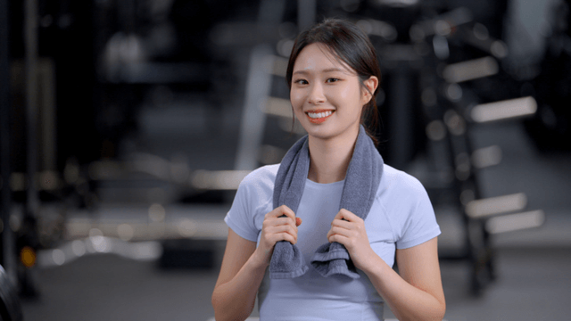 Young woman facing forward with a towel around his neck at gym