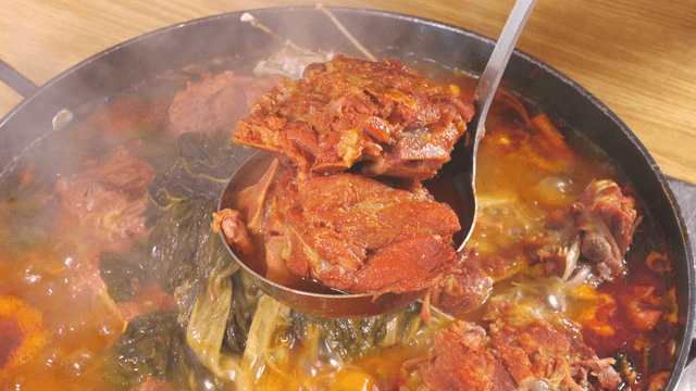 Ladle filled with pork back-bone meat and outer leaves stew