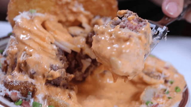 Burger dipped in cheese sauce with a fork