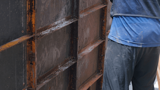 Worker handling wooden planks at a construction site