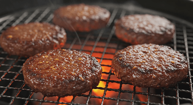 Juicy burger patties grilling over flames
