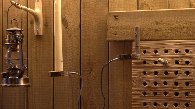 Artisan placing a candle on a wooden wall with a lantern