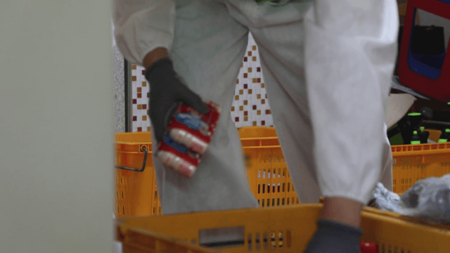 Person putting groceries into a yellow basket