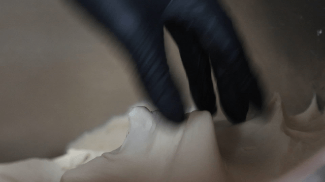 Gloved hands mixing dough