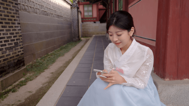 스마트폰을 사용하는 한복 입은 여성