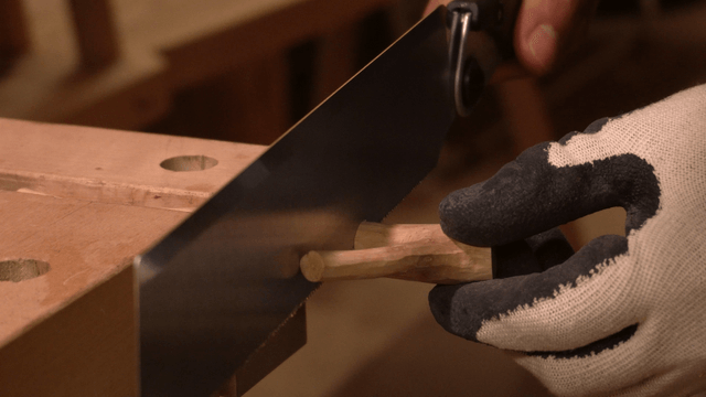 Hands cutting fixed wood with a saw