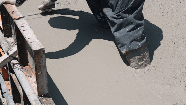 Worker smoothing wet concrete surface