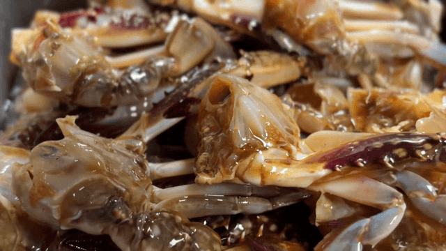 Marinated crabs being covered with special soy sauce