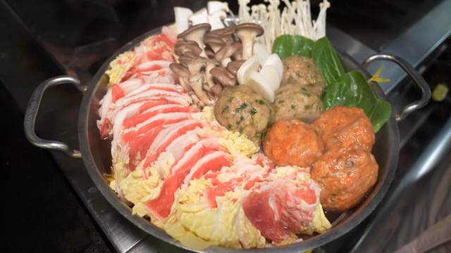 Broth being poured over hot pot ingredients