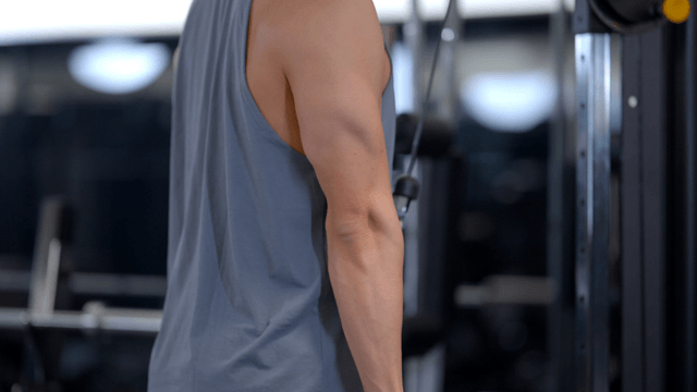 Man doing arm pulldown workout with rope at gym