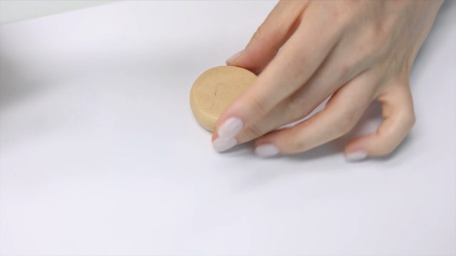 Hands rolling clay on a white surface