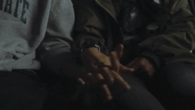 Two people holding hands in a dimly lit space