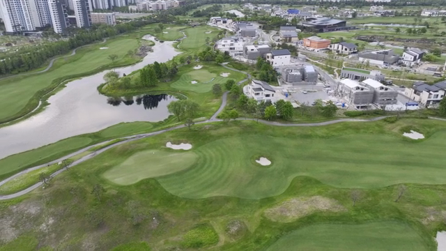 A golf course near a modern cityscape