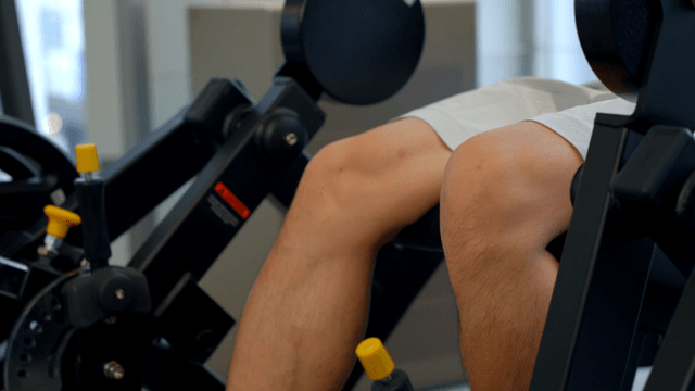 Young man doing leg workout on a machine in a gym
