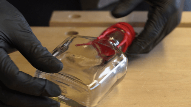 Hands holding a glass bottle with red wax