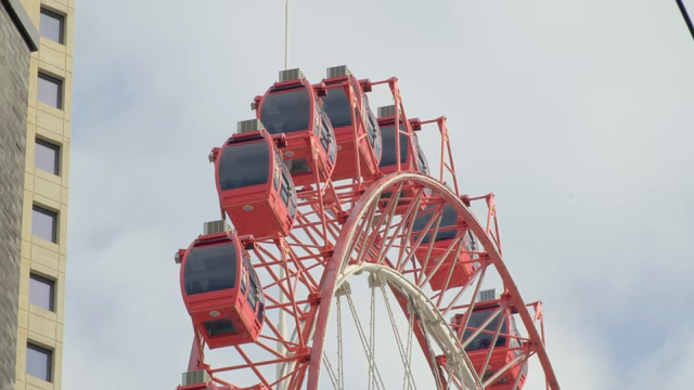 Red Ferris wheel against a city backdrop