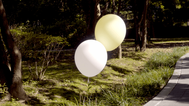 Two balloons rising beside a walkway