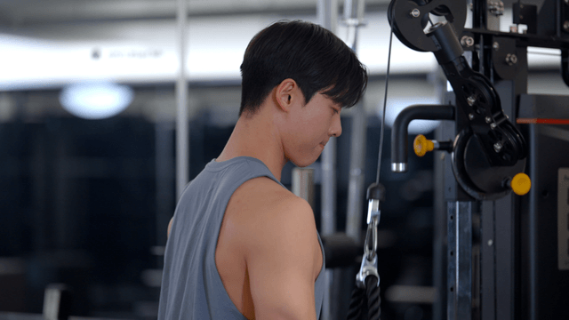 Man training arms with rope in gym