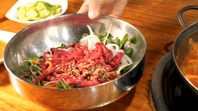 Kimchi stew and yukhoe bibimbap on wooden table