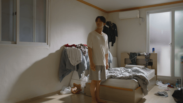 Man standing in a messy bedroom