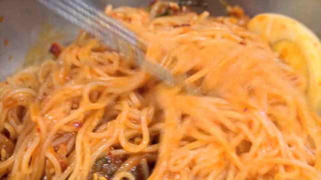 Spicy noodles being mixed in a bowl